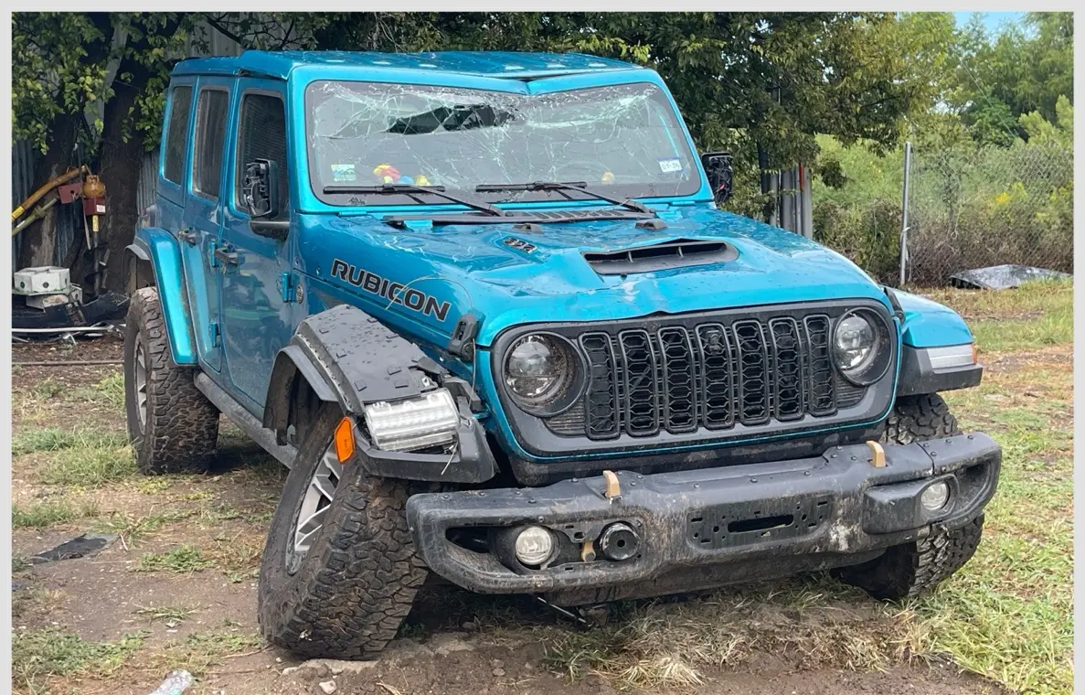 Blue Jeep Wrangler Rubicon with front-end, fender, windshield, and body damage before repair at Raymond's Paint & Body